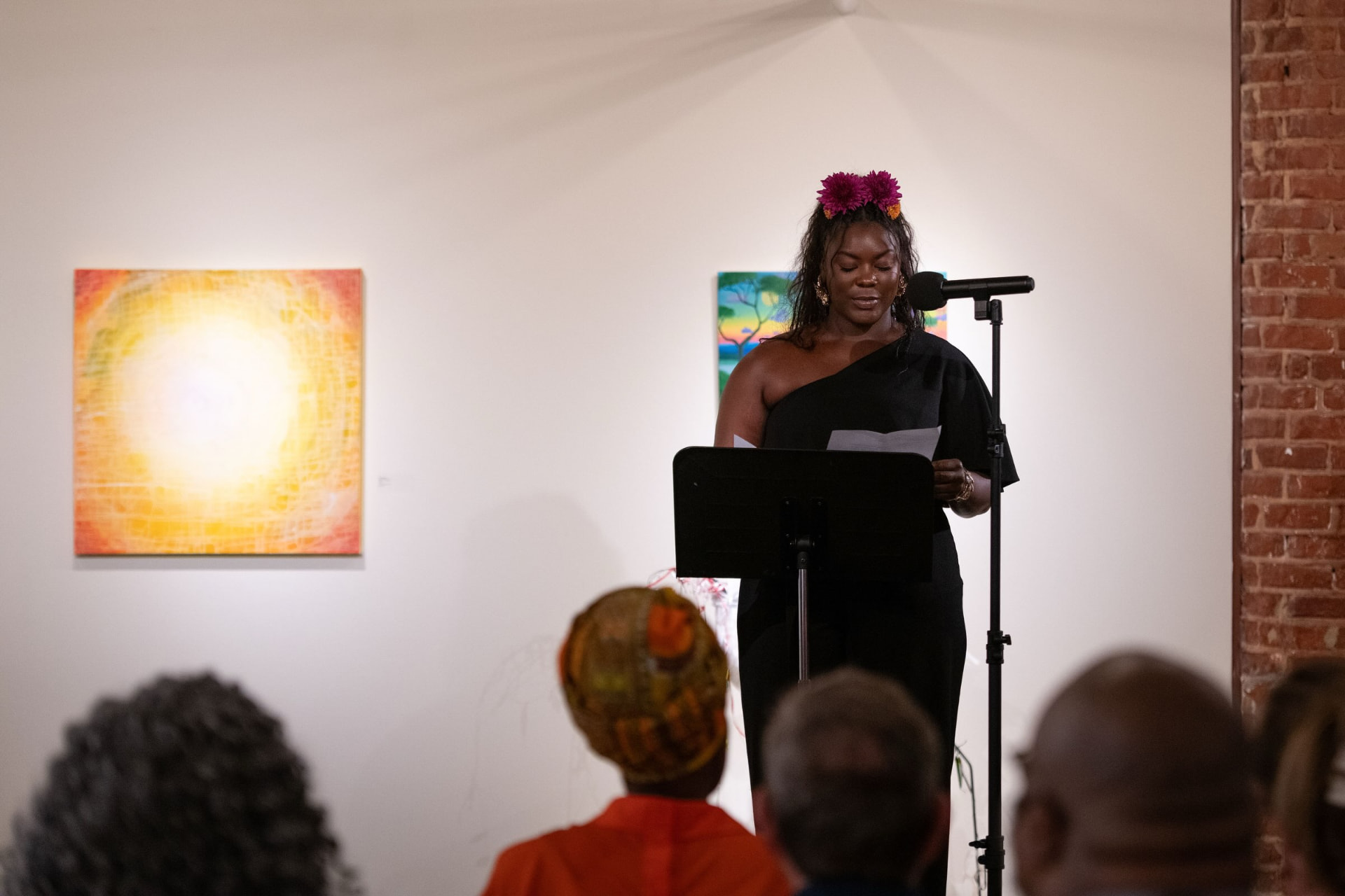 Jasmine Ballard performing The Last Interview at a microphone in a gallery.